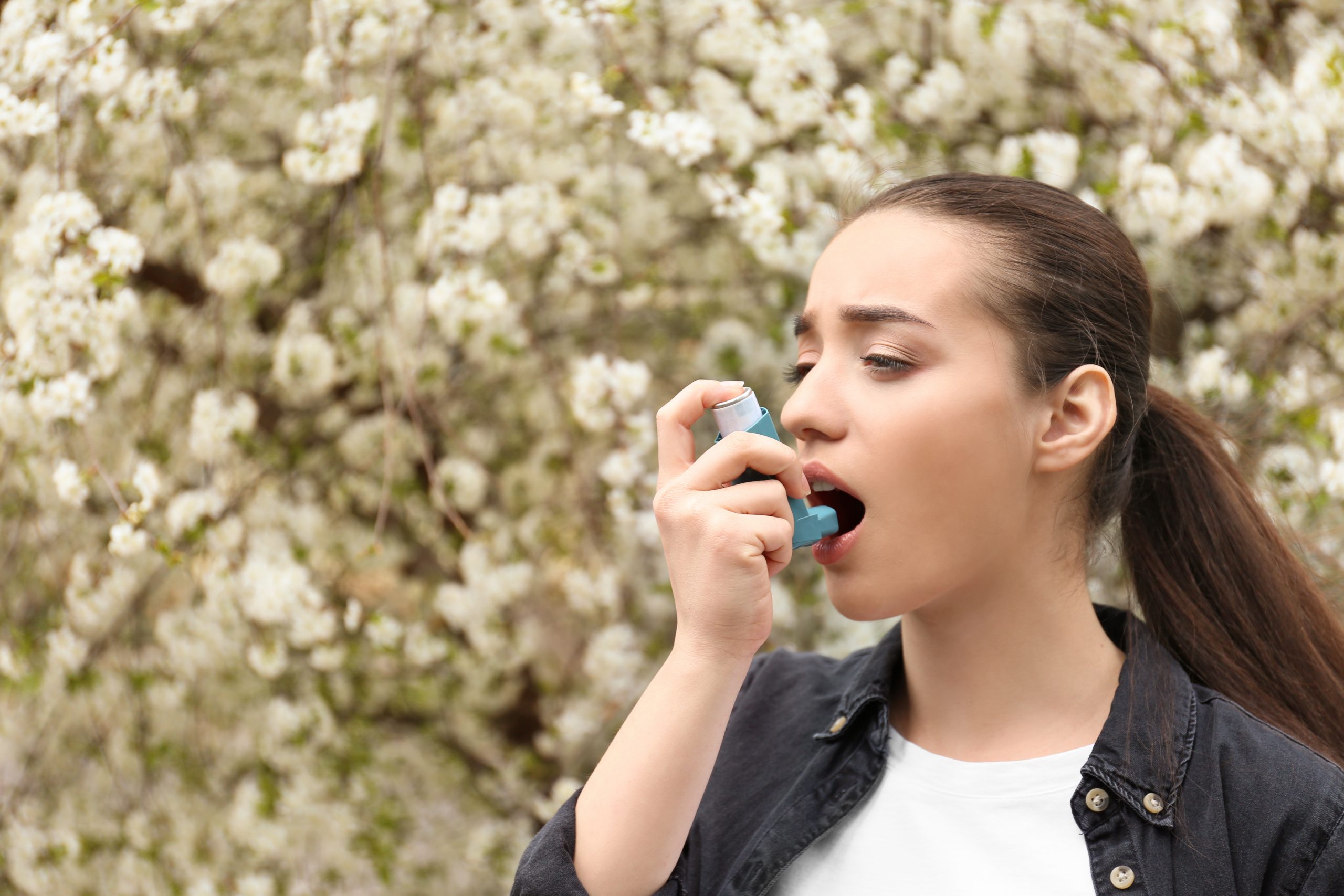 Woman using inhaler during spring time