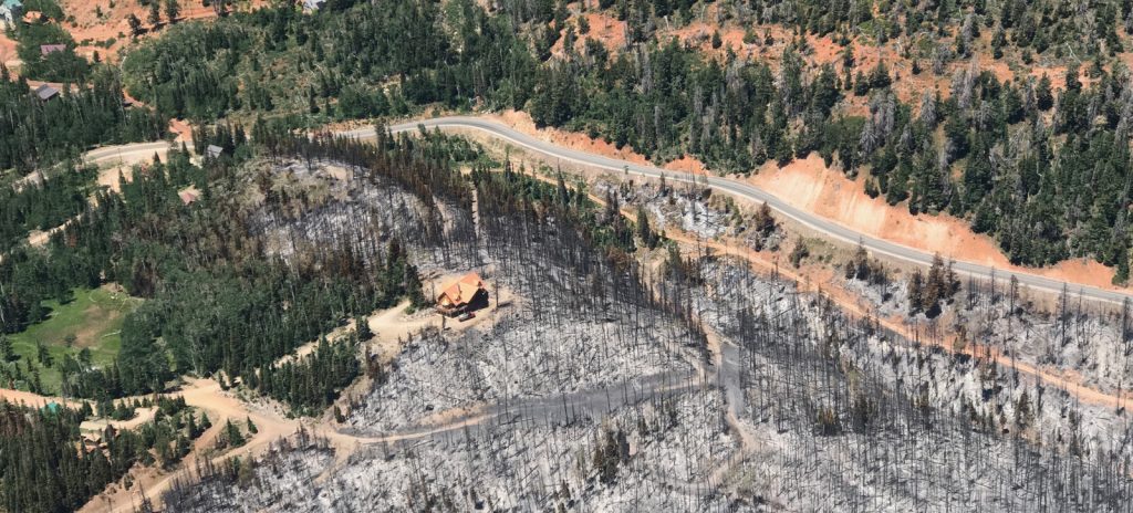 aerial view of a burned out area with a cabin that appears to have survived the fire