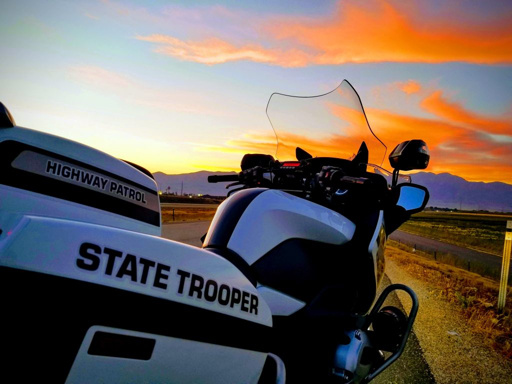 A UHP motor sits on the road shoulder with a Utah sunset lighting the sky. UHP troopers will work an additional 341 extra shifts over the Labor Day weekend