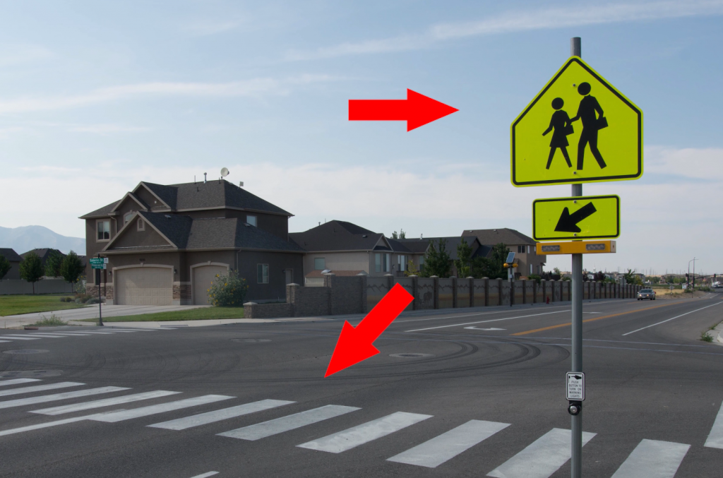 If you see two people on the pedestrian sign and ladder bars on the roadway, you're at a school crosswalk, which means you have to stop for anyone in the crosswalk, regardless of which half of the roadway they're on.