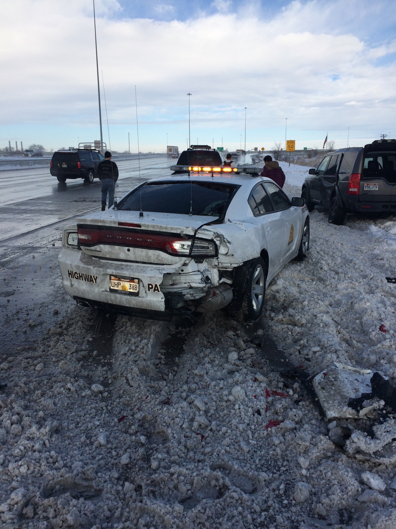 A UHP trooper's vehicle received significant damage when a car crashed into it on the road shoulder.