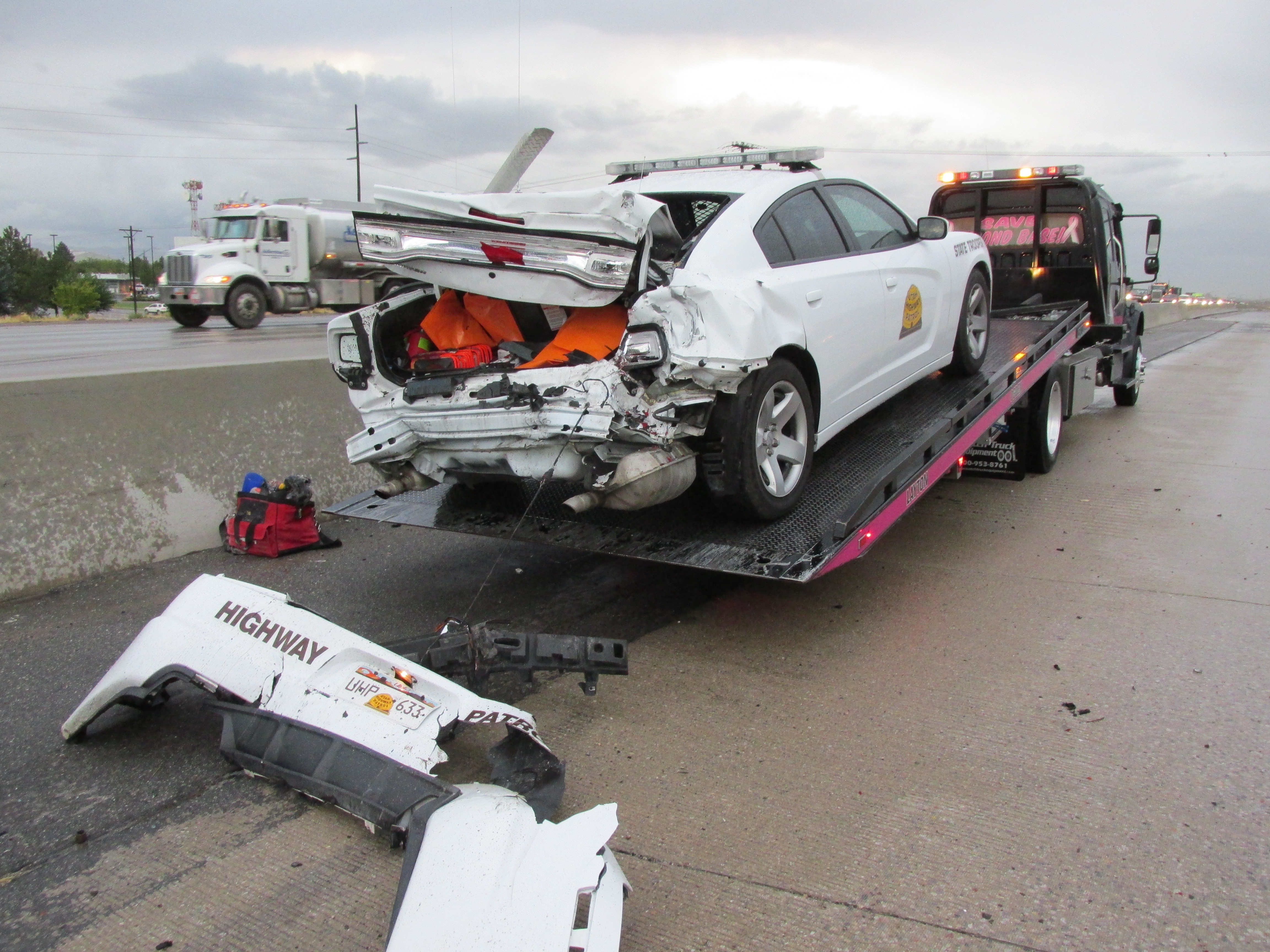 A UHP trooper's vehicle received significant damage when a car crashed into it on the road shoulder.