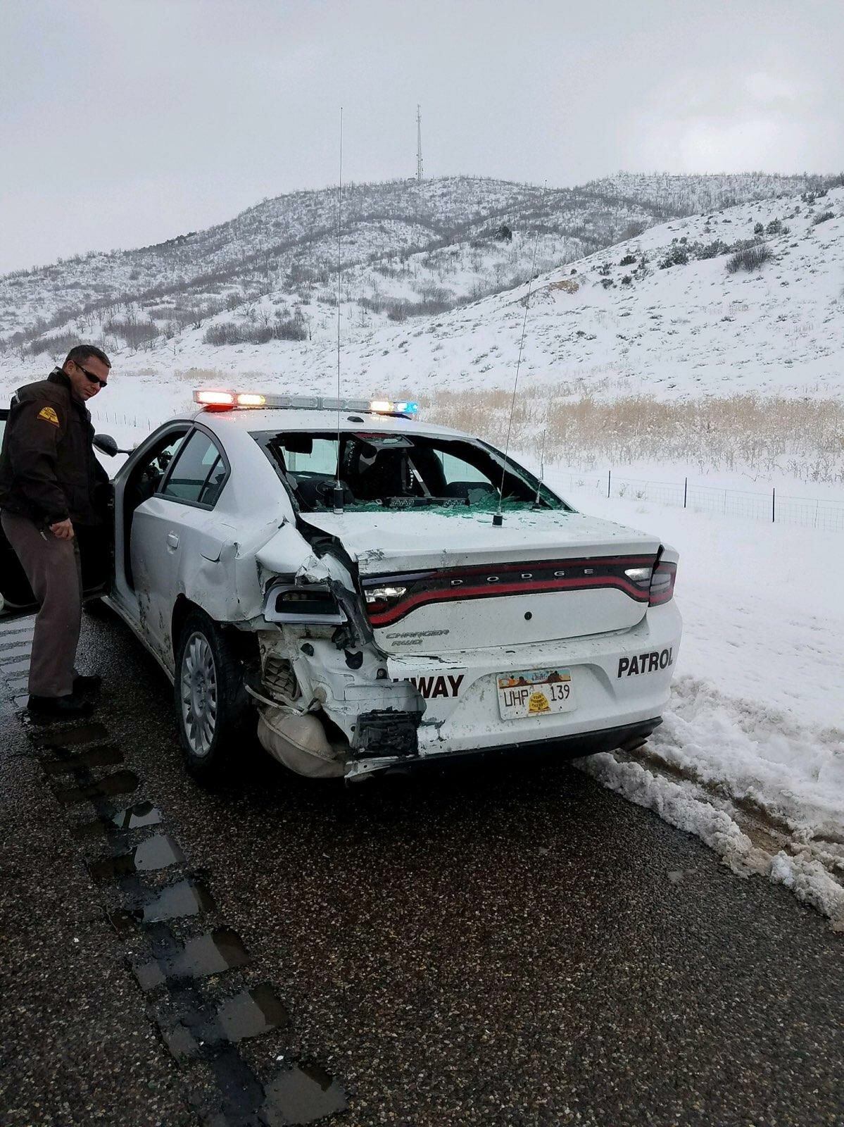 A UHP trooper's vehicle received significant damage when a car crashed into it on the road shoulder.