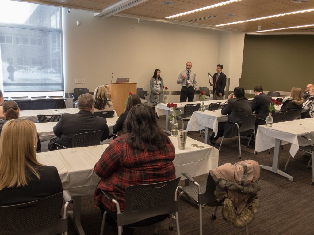 Managers outline the contributions employees make to the crime lab during the promotional ceremony.