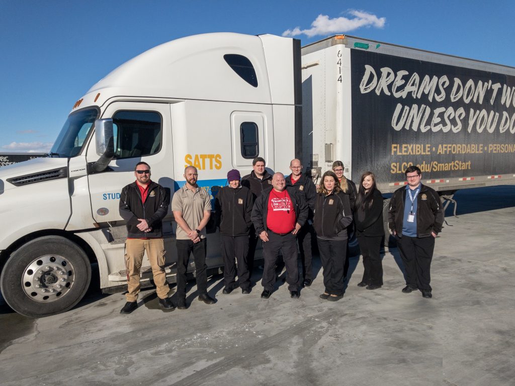 Students and instructors from the CDL examiner class pose by a semi truck used for training