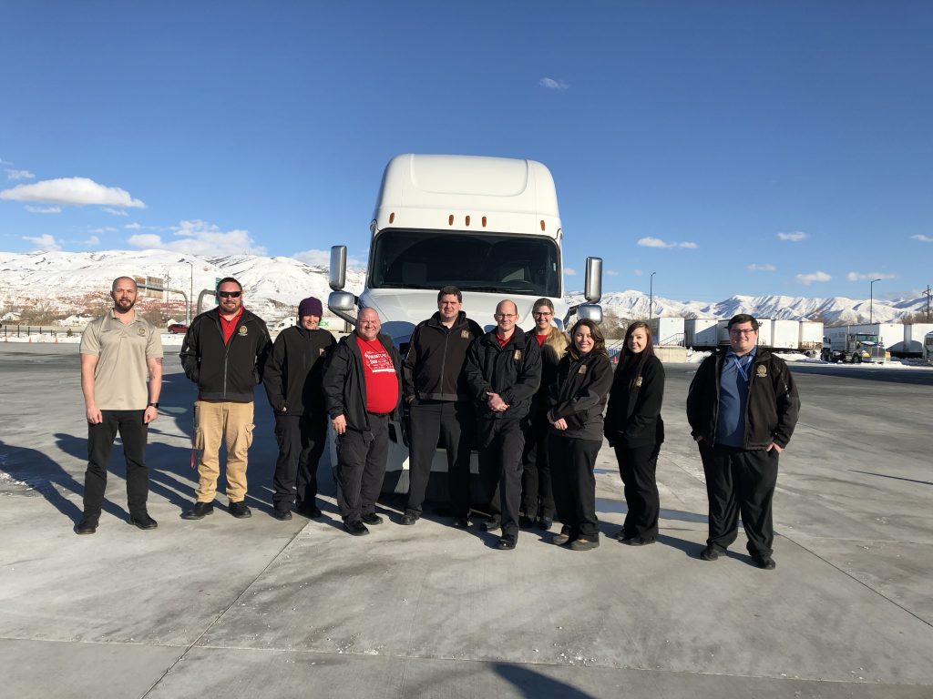 DLD participants in the CDL examiner class pose in front of a semi truck used for training