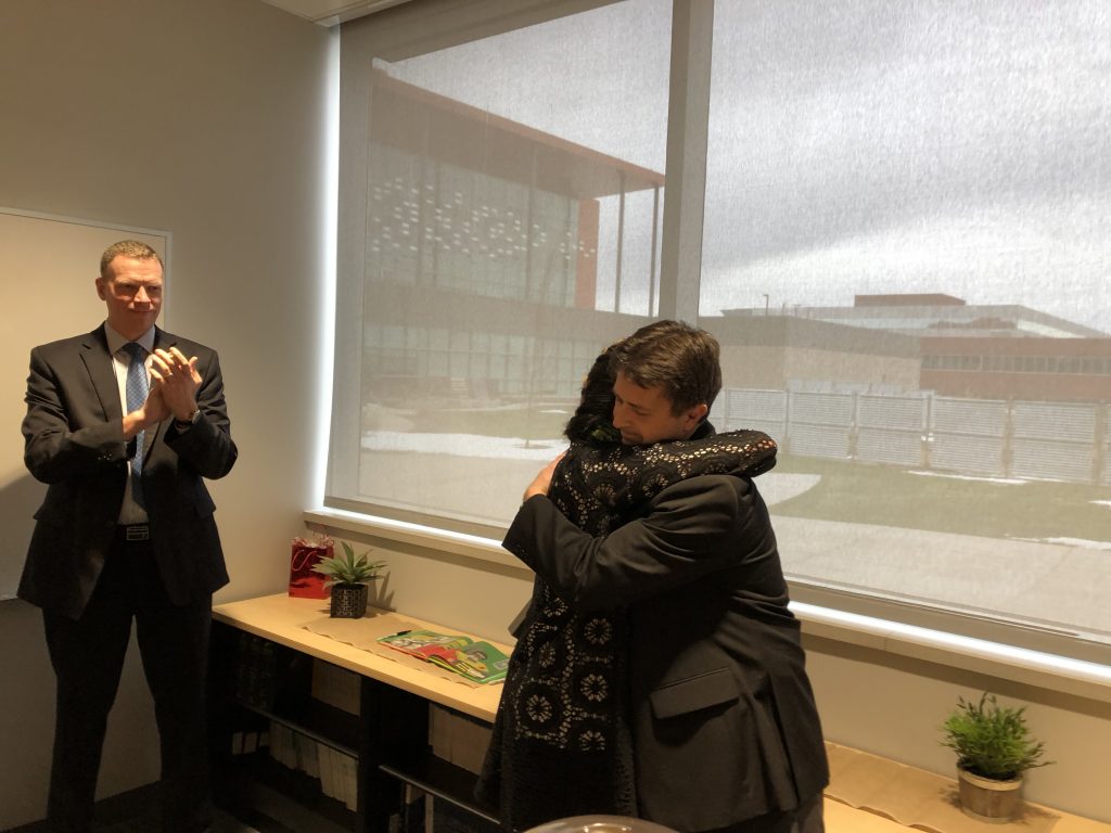 Jay Henry gives Pilar Shortsleeve a hug to congratulate her on her retirement as Commissioner Anderson looks on.