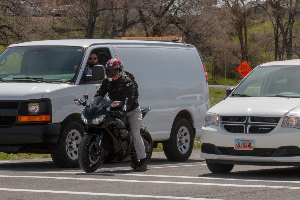 A motorcyclist waits for a light to turn green after filtering between lanes of stopped vehicles.