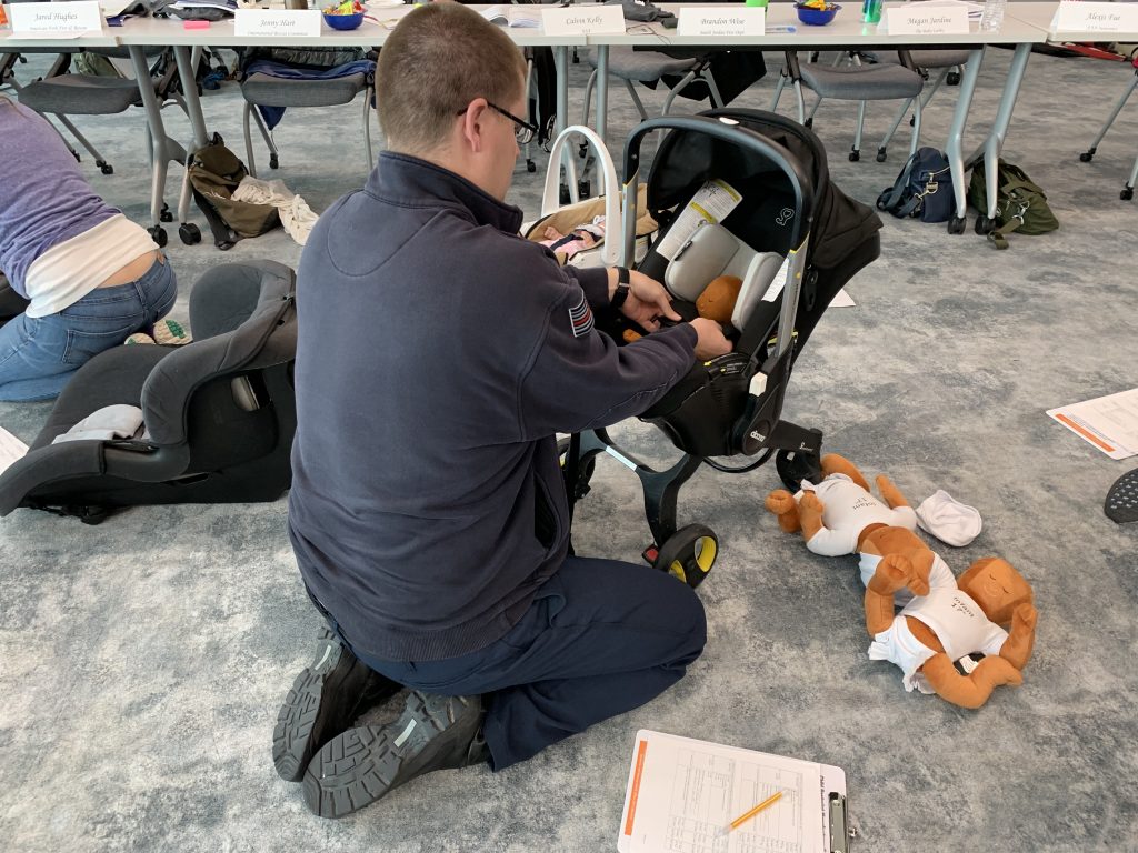 A student in the CPS class straps a mannequin into a car seat.