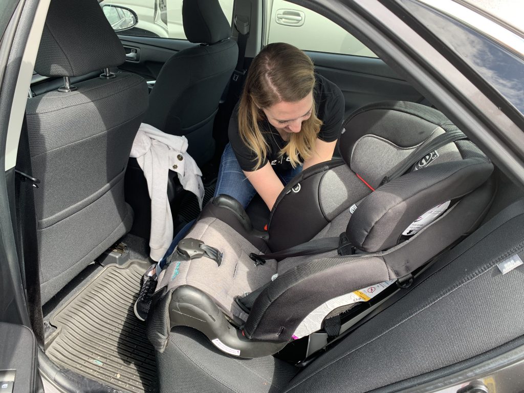 A student in the CPS class works to correctly install a car seat.