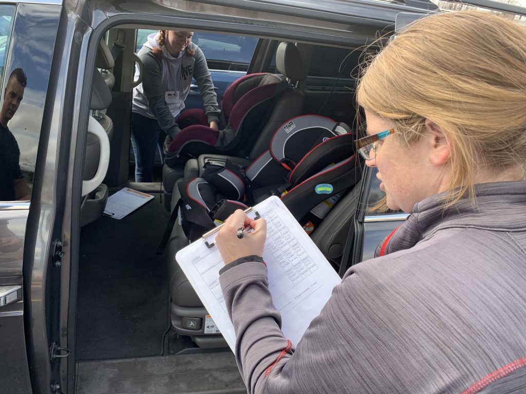 Car seat technician instructor checks the installation of a car seat