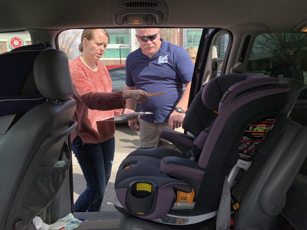CPS instructor reviews a student's installation of a car seat.
