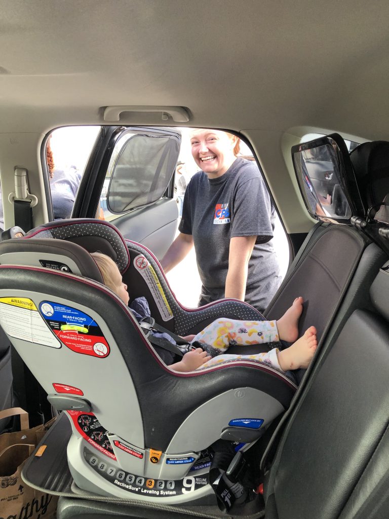 A car seat technician helps install a car seat at a check point.